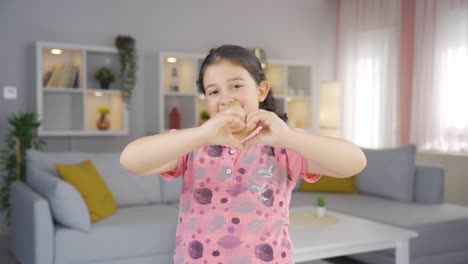 Girl-child-making-heart-sign-at-camera.